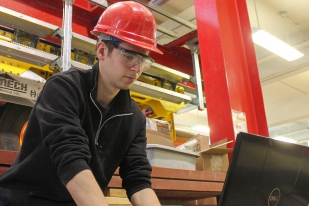 student in hard hat looking at equipment