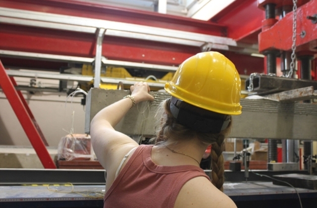 female student in hard hat working on research