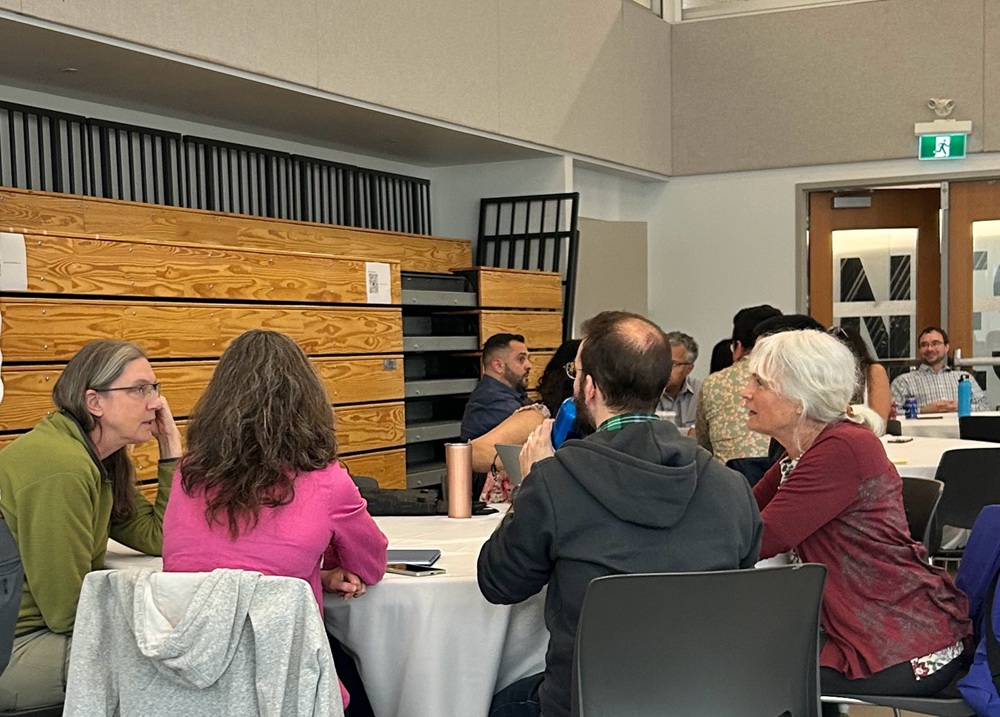 Small group of people seated around a round table, talking during a workshop.