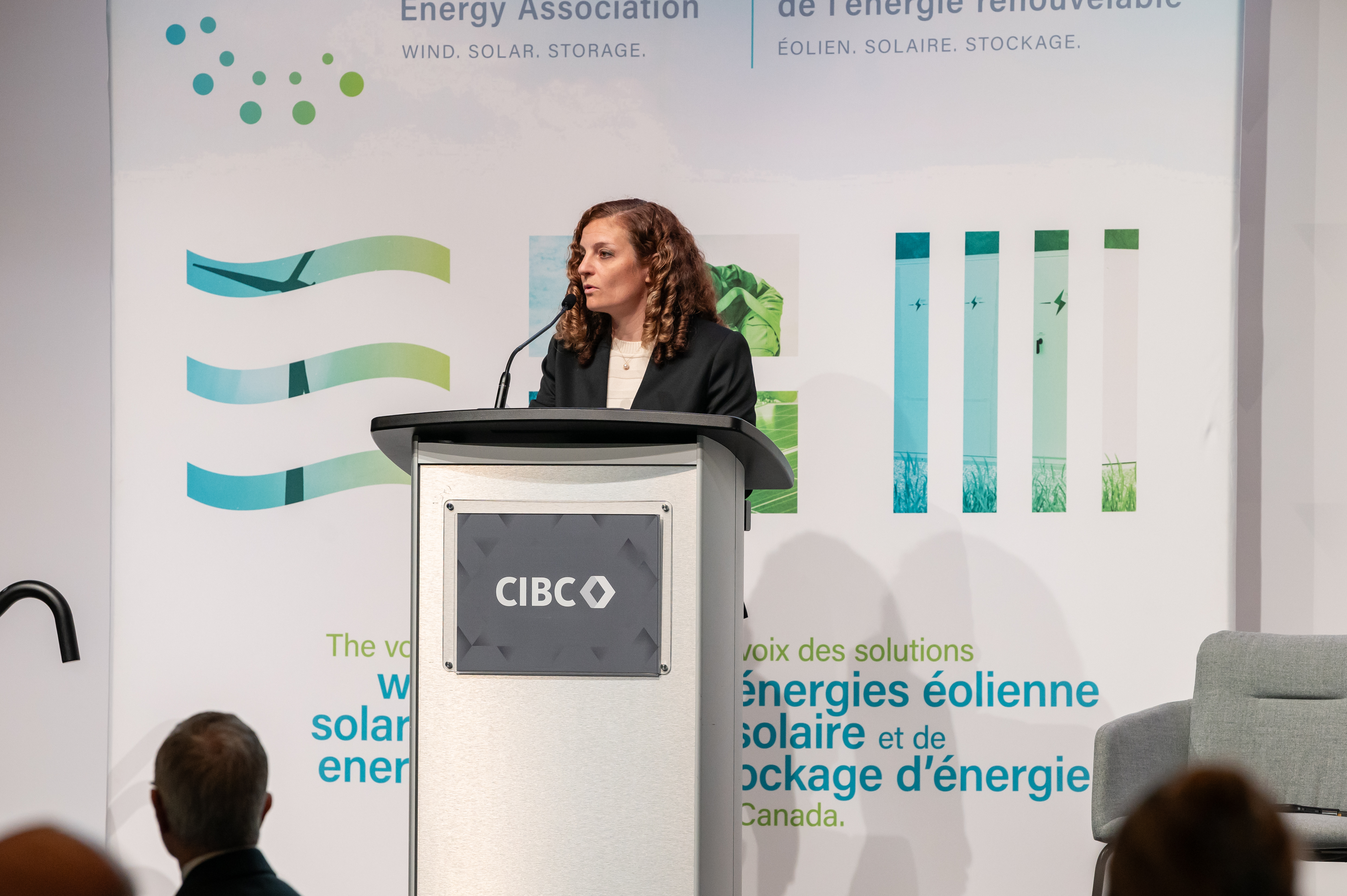 Woman with light brown curly hair standing at a podium giving a talk